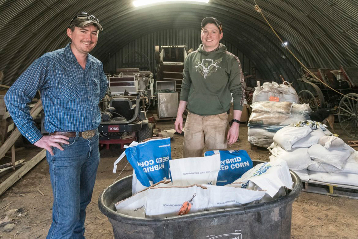 Dallas Glazik (right) and brother Will Glazik with some of the corn varieties they grow on their farm near Paxton, IL on Friday, April 13, 2018. (Photo by Darrell Hoemann/The Midwest Center for Investigative Reporting)