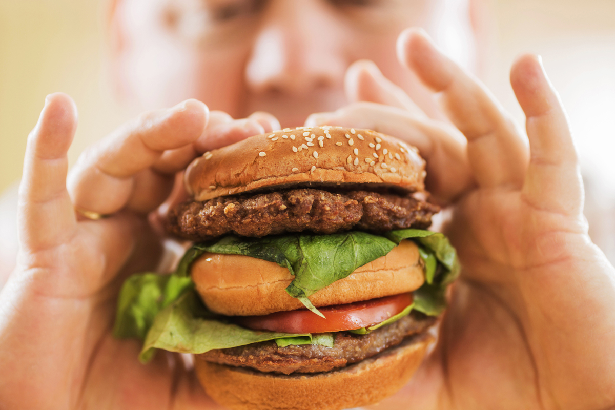 a person eating a large hamburger