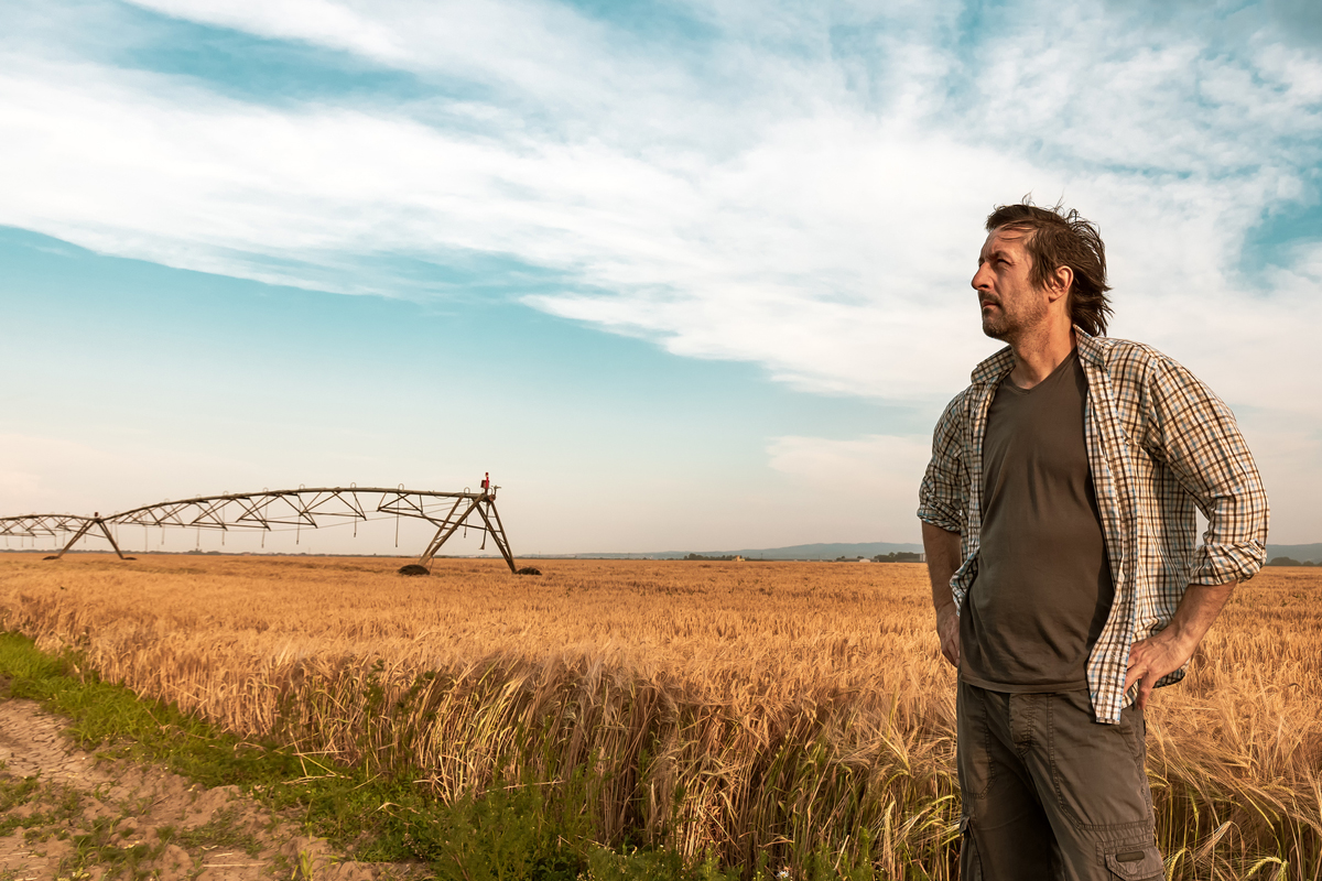 worried farmer standing in his farm field