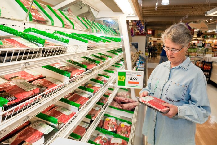 a woman inspecting packaged meat for a country of origin label. USDA photo by Stephen Ausmus.