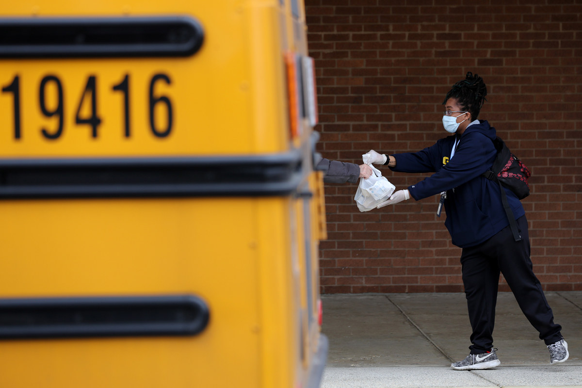 A Montgomery County (Maryland) Public Schools worker helps distribute bags of donated food as part of a program to feed children while schools are closed due to the coronavirus. (Photo by Chip Somodevilla/Getty Images)