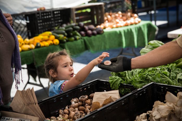 A girl pays for her mother's groceries using Electronic Benefits Transfer (EBT) tokens at the GrowNYC Greenmarket in New York City's Union Square. (Photo credit: Andrew Burton/Getty Images)