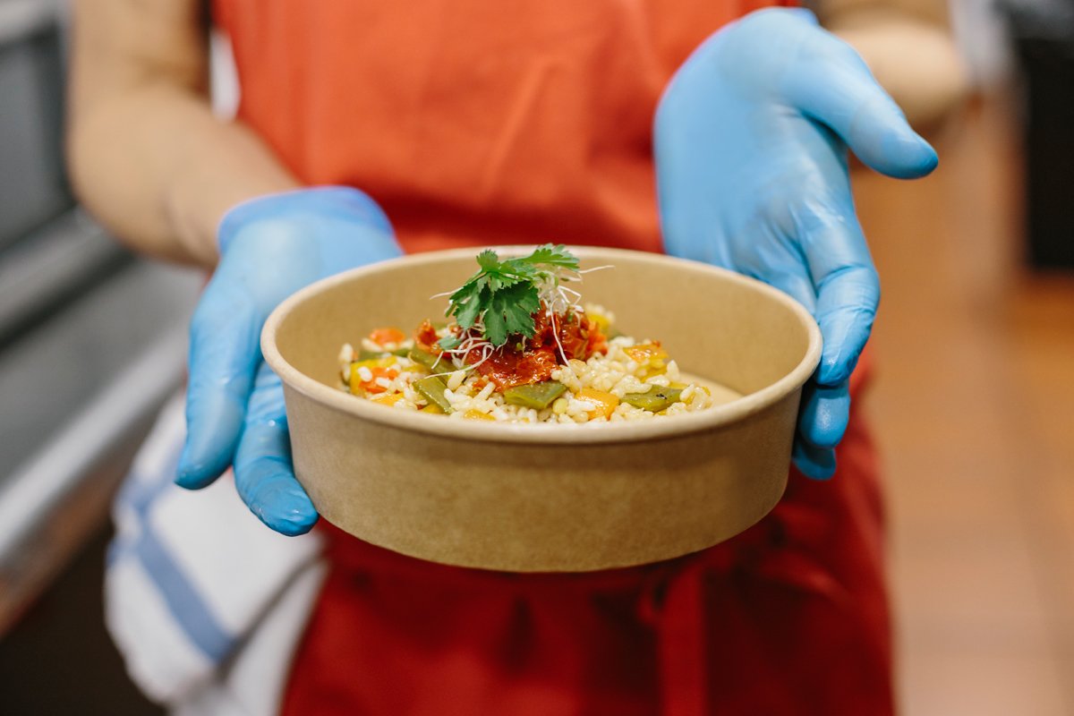 Food service worker holding a compostable container made with PFAS and forever chemicals.