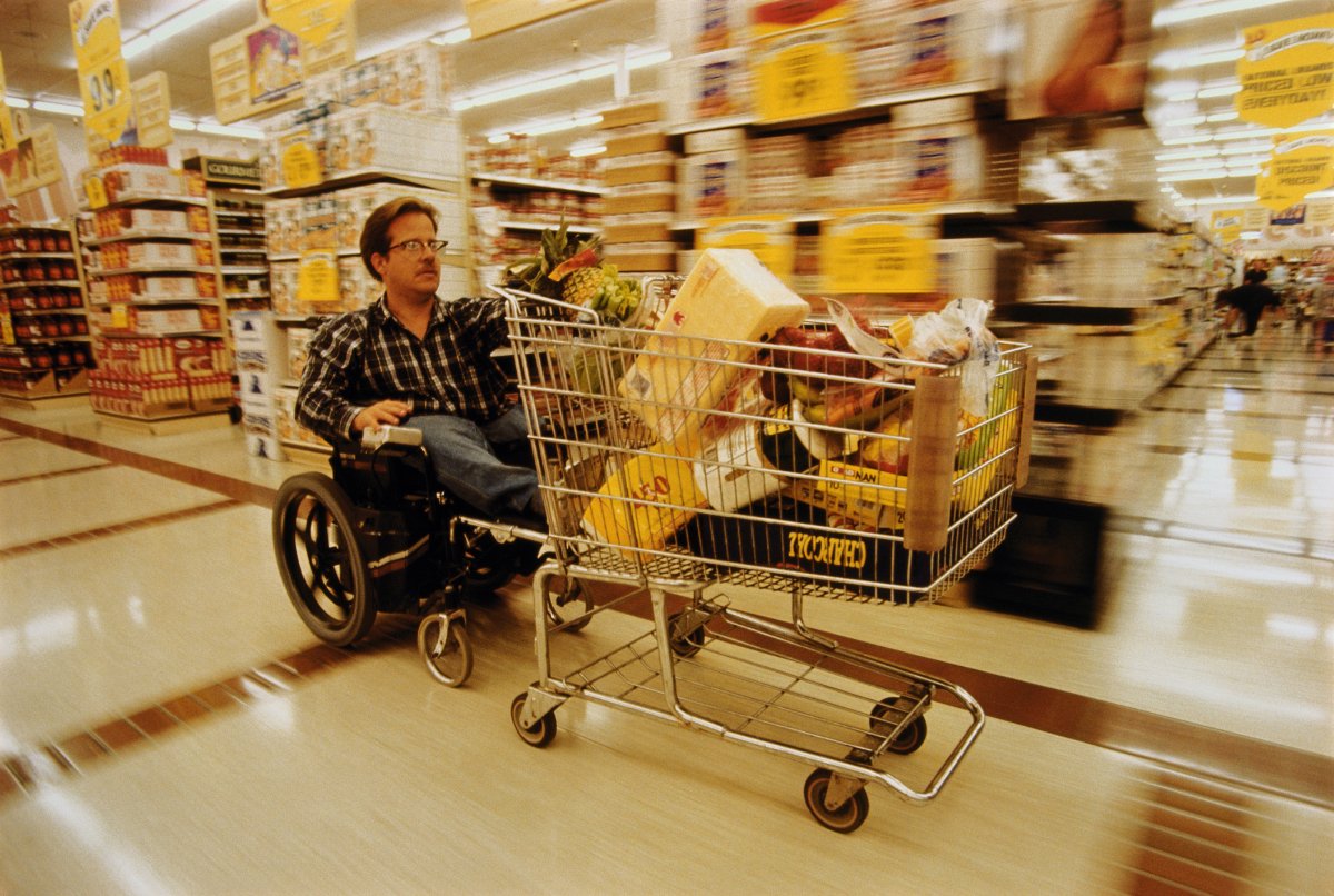 A disabled person in an electric wheelchair shops for groceries in a supermarket even though food price inflation is making it harder.